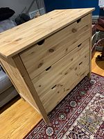 Front angle view of a solid wood dresser showing three drawers and natural wood finish.