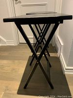 Side view of one folding TV table showing the X-frame foldable legs and rectangular top with a dark wood finish.