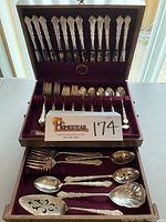Overview of the wooden chest with all flatware pieces arranged in designated slots on burgundy velvet lining.