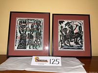 Two framed watercolor prints by Nigerian artist Bayo Ogundele featuring abstract black figures on a multicolor background, double matted and framed.
