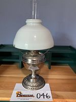 Full view of the complete Bradley & Hubbard nickel plated oil lamp with white opal glass shade and glass chimney, displayed on wooden surface