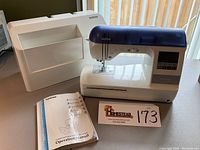 Full view of the Brother Innovis 1200 sewing machine with hard plastic carrying case and operation manual displayed on a table.
