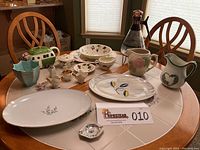 Tabletop view showing assortment of pottery and china including platters, bowls, creamers and teapot