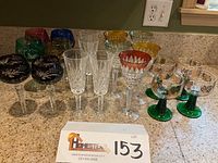 Full lot of various German crystal stemware glasses arranged on countertop, showing assortment of colors and styles