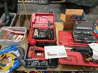 Table of assorted power tools and cases including Skil scroll saw and reciprocating saw.