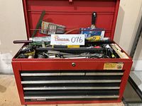 Front view of red Sears Craftsman steel toolbox chest with lid open, showing top compartment filled with assorted hand tools and accessories.