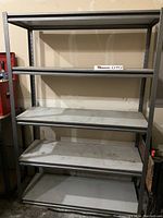 Full view of the metal shelving unit showing all four shelves and the sturdy metal frame in a garage setting.