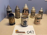 Front view of all eight West Germany beer steins arranged on table with lot number card