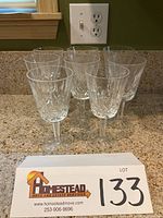 Eight clear crystal water stems arrayed on countertop with outlet in background