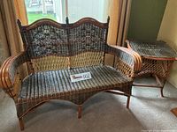 Full view of wicker bamboo loveseat and matching side table showing overall condition and size.