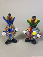 Two multicolored Murano blown glass clown figurines side by side, showing front view and size perspective.