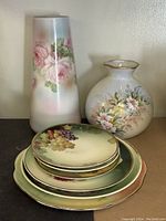 Photo showing two vases and stacked plates, highlighting Limoges vase and floral decorated plates