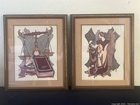 Pair of framed Ian Kochberg lithographs with beige matting and gold-toned frames side by side on a black surface