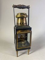 Front angled view of the brass nautical ship lantern showing the handle, vent, glass door, and legs.