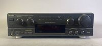 Front view of the Technics SA-AX540 stereo receiver showing power button, control knobs, headphone jack, and digital display.