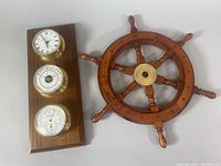 Weather station and ship wheel side by side on light surface showing overall condition and scale.