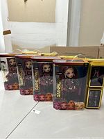 Four Rainbow High dolls in original window display packaging showing dolls dressed in various colorful outfits, posed with hands on hips, displayed from front angle.