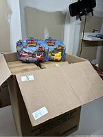 Box containing multiple boxes of Mighty Express Motorized Toys with Rescue Red and Rocky characters visible.