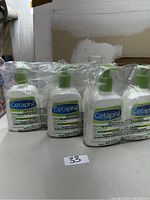 Photo showing 4 of 6 bottles of Cetaphil lotion, two sets of 2 bottles on a table.