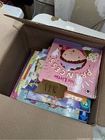 Box of children's books with multiple colorful illustrated covers visible, including one titled "Pruncess".