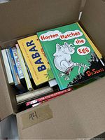 Box opened showing several colorful children's books including 'Horton Hatches the Egg' by Dr. Seuss and 'Babar' books.