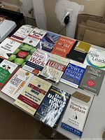 Photo of a table displaying a variety of business and leadership books with mostly paperback covers, arranged neatly in rows.