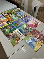 Lot of 11 Disney story books arranged on table, colorful covers visible showing various Disney characters and titles.