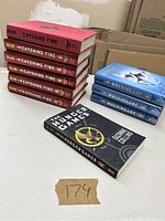 Six copies of Catching Fire, three copies of Mockingjay, and one copy of The Hunger Games laid on a table.