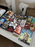 Books arranged side-by-side showing front covers, highlighting Tom Clancy and Lee Child books with some Halo series novels