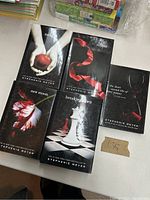 Photo of five hardcover Twilight series books laid flat showing front covers including Twilight, New Moon, Eclipse, Breaking Dawn, and The Short Second Life of Bree Tanner.