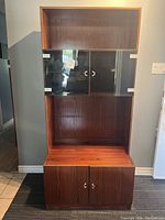 Full view of assembled two-piece mid century modern Danish rosewood cabinet by Denka, showing upper glass door shelving and lower wood doors.