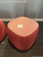 Front view of red fabric ottoman showing overall shape and fabric