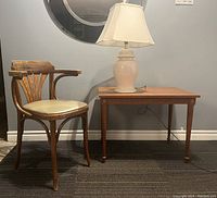 View of bentwood chair, ginger jar table lamp, and walnut end table against wall