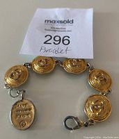 Photo of vintage gold-tone Chanel bracelet showing round medallions with double C logo and attached oval tag stamped Chanel Made in France Paris