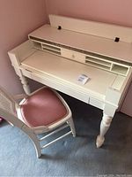 Photo showing the white secretary desk with organization cubbies, flat writing surface, and matching chair with pink cushion from the front angled view.
