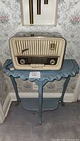 Front view of Telefunken vintage radio on blue wooden end table showing radio grille, knobs, and table details