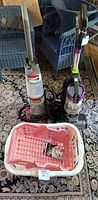 Photo showing Hoover Power Path Deluxe Carpet Washer, Bissell Pet Hair Eraser Vacuum, and multiple storage baskets on a carpeted floor.