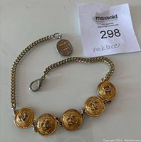 Full view of gold tone necklace with five circular medallions each featuring the Chanel CC logo and attached chain with lobster clasp and coin charm.