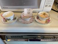 Photo showing three teacup and saucer sets side by side on countertop