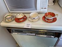 Four teacup and saucer sets arranged on kitchen counter showing various designs and styles