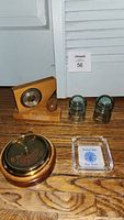 Photo of the two weather barometers, glass insulators, ashtray, and shot glasses arranged on wooden floor