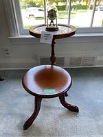 Full lot view with wine table, plant stand, and dome clock placed near a window for lighting.