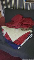 Photo of dark red, white, and blue blankets piled on a dark gray couch