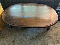 Top view of oval dark wood coffee table showing scratches and wear, with visible central seam for extension.