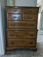Front view of two-piece wooden dresser with six drawers in varying sizes showing hardware and finish.