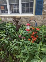 Wooden reindeer planter, red hummingbird feeder hanging from shepherd's hook in garden