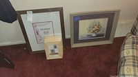 Photo showing large brown 16x20 frame, five smaller light wood frames arranged on floor, and framed floral print with brown frame.