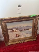 Front view of the framed painting depicting a snowy winter scene with figures and cottages under mountains.