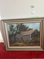 Frontal view of the framed landscape painting depicting a rustic house surrounded by trees and flowers, signed by Florence M Higgins.