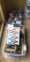 Overview of plastic tubs filled with jewelry making supplies including pliers, bead containers and books